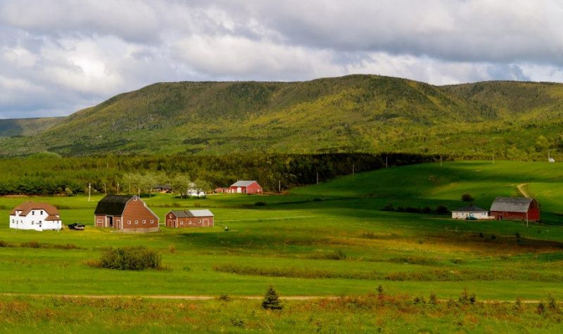 Trois maisons et trois granges dans une vallée.