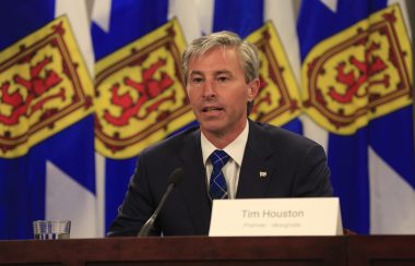 Tim Houston en conférence de presse devant des drapeaux de la Nouvelle-Écosse