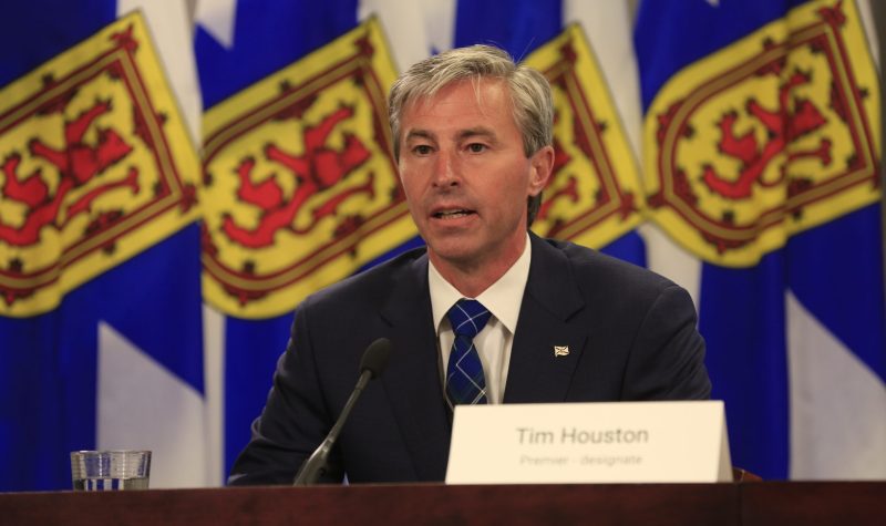 Tim Houston en conférence de presse devant des drapeaux de la Nouvelle-Écosse