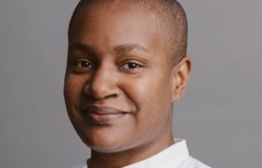 A woman in a white shirt against a grey background.