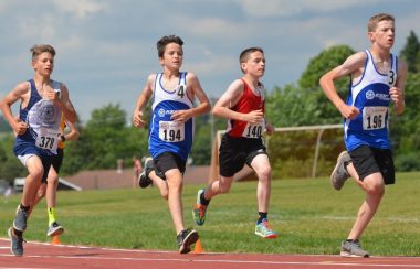 Quatre jeunes garçons participant à une course à pieds.