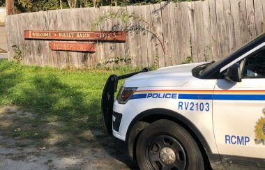 RCMP car in front of a gate with a sign on it that says Bullet Basin