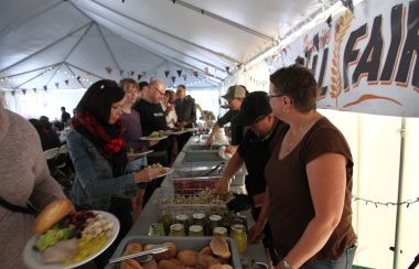 People are served buffet-style under a tent.