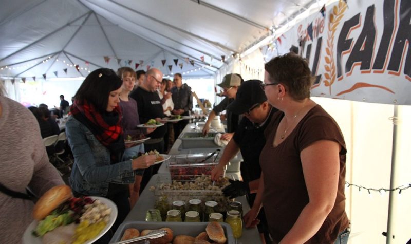 People are served buffet-style under a tent.