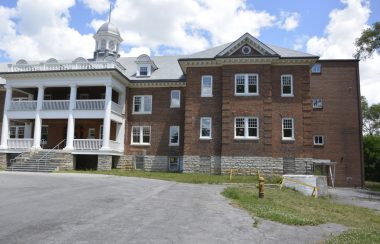 The front left side of brick dormitory building on a summer day.