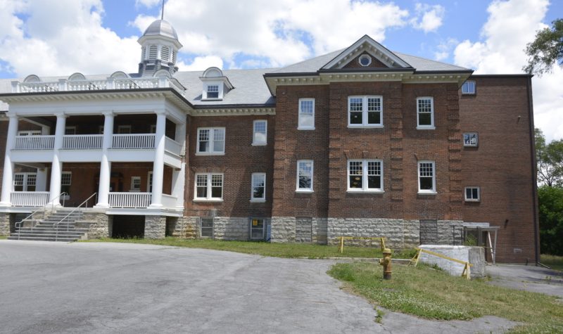 The front left side of brick dormitory building on a summer day.