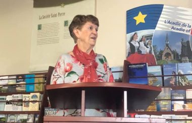 Une dame debout à un podium avec des étagères de dépliants en arrière plan.