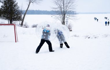 Two children enjoying so winter fun by playing bubble soccer.
