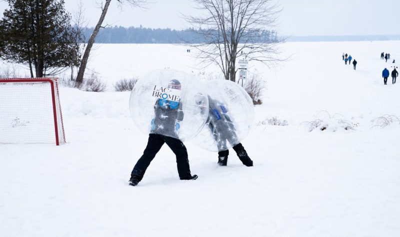 Two children enjoying so winter fun by playing bubble soccer.