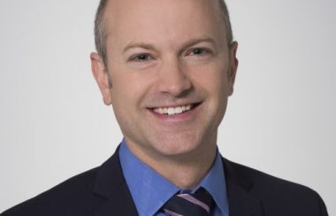 A person in a suit with a blue dress shirt and tie.