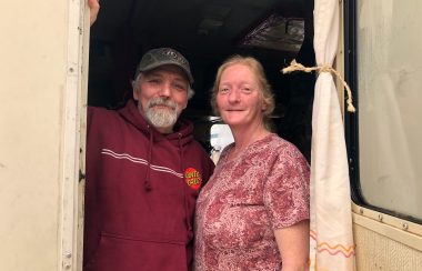 A man and a woman stand in the door of an RV.