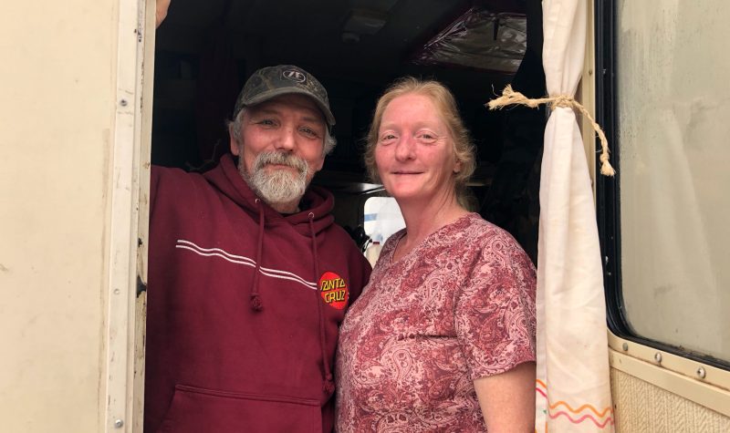 A man and a woman stand in the door of an RV.