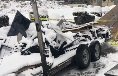 Charred debris covered in snow on a trailer.