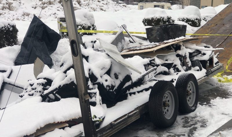 Charred debris covered in snow on a trailer.