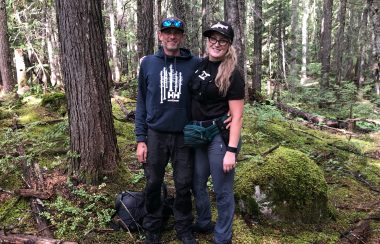 Two people standing in the forest.