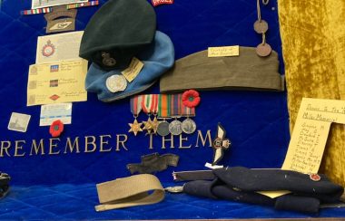 A trophy and display case from the legion branch 249 in houston bc shows military hats, letters home, poems written and badges of honour.