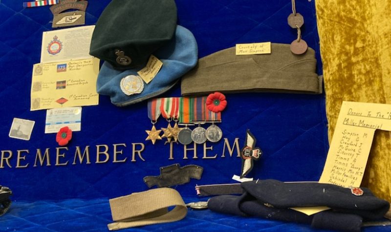 A trophy and display case from the legion branch 249 in houston bc shows military hats, letters home, poems written and badges of honour.