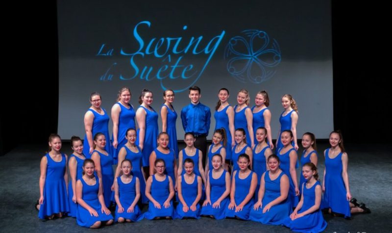 Des jeunes habillés en bleu en avant d'un tableau avec l'écriteau La Swing du Suête.u