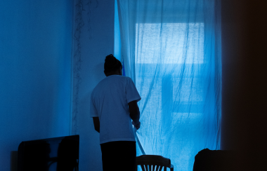 un joven observa temeroso por una ventana. Foto: canva.com