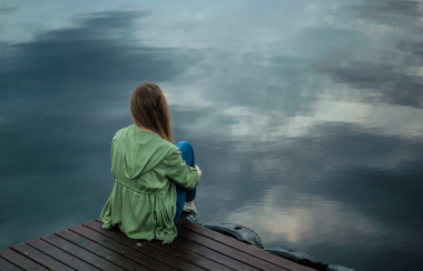 Una persona mira hacia un lago. Foto: Canva