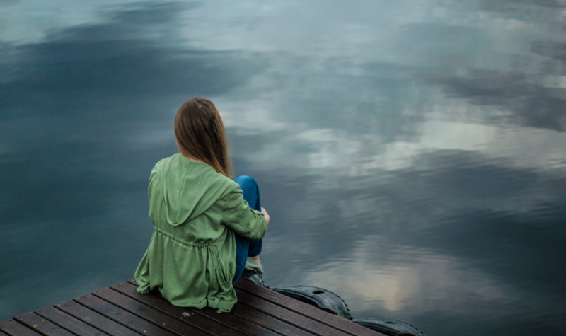 Una persona mira hacia un lago. Foto: Canva