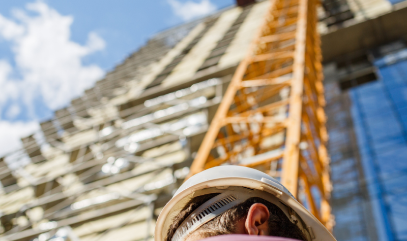 Un hombre de espaldas mirando un edificio en construcción. Foto: Canva.com