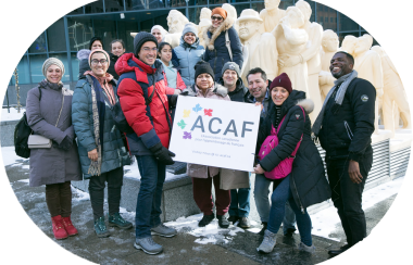 Les membres de l'association tiennent un carton inscrit ACAF et sont habillés pour l'hiver