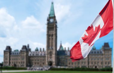 Canadian flag waving with Parliament Buildings hill in the background Ottawa,Ontario, Canada