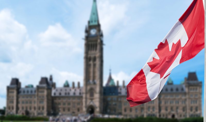 Canadian flag waving with Parliament Buildings hill in the background Ottawa,Ontario, Canada