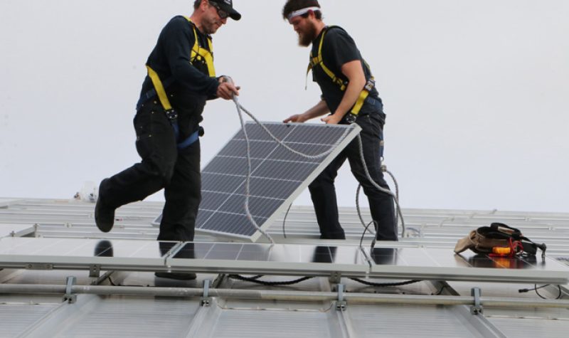 Workers installing rooftop solar panels. Photo: amherst.ca