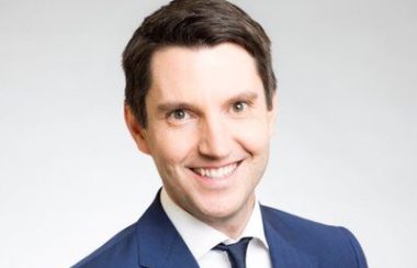 A professional headshot of André Fortin, wearing a blue suit and tie.