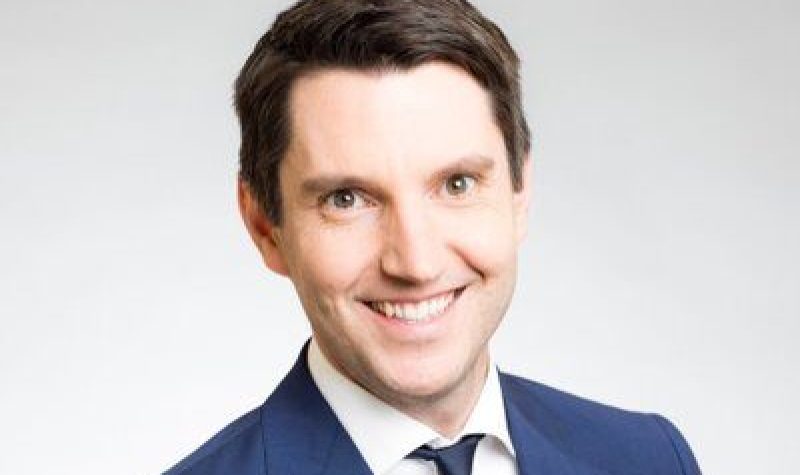 A professional headshot of André Fortin, wearing a blue suit and tie.