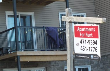 Un panneau indiquant des appartements à louer devant un immeuble d'habitation