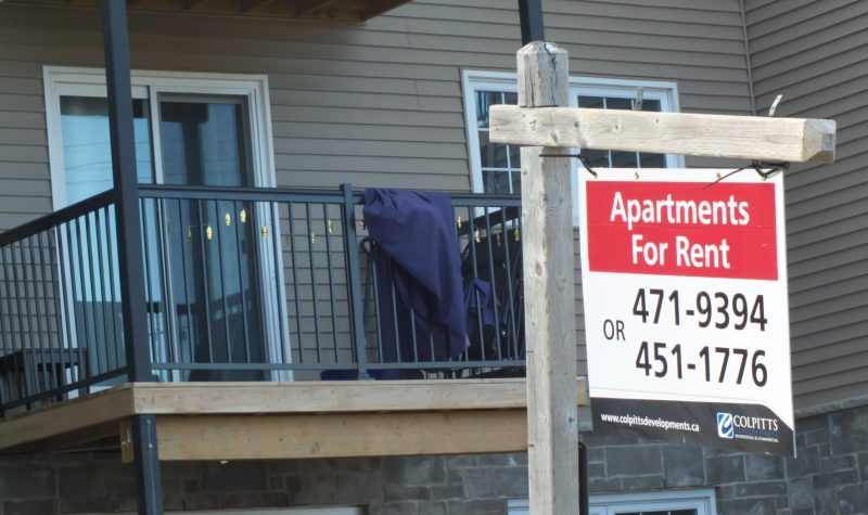 Un panneau indiquant des appartements à louer devant un immeuble d'habitation
