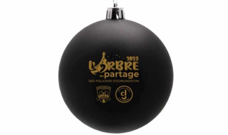 Une boule de Noël de couleur noir et or avec les mots Arbre du Partage écrits dessus.