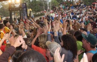 Une foule aux mains agitées regarde un concert.