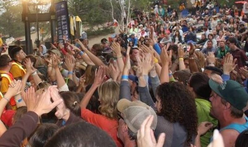 Une foule aux mains agitées regarde un concert.