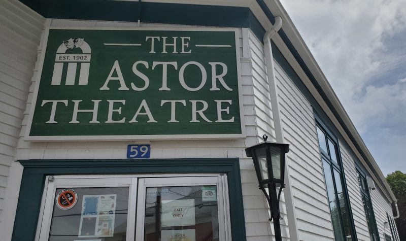 Sign for the Astor Theatre above glass double-doors in a white building