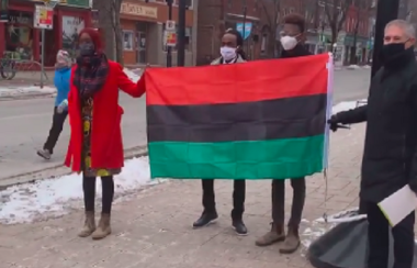 Three Black Lives Matter organizers stand with the Fredericton mayor and hold the Pan-African flag.