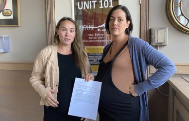 Jen Mio and Emilie Schmit holding their letter in front of Nathan Cullen's office