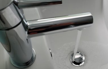 A bathroom tap pours water into sink