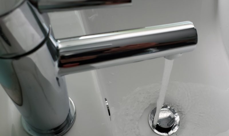 A bathroom tap pours water into sink