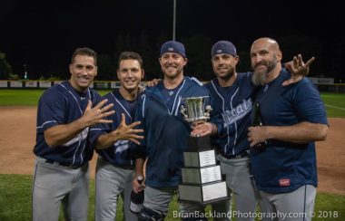 5 membres des Baycats de Barrie célébrant leur championnat, trophé à la main.