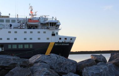 De grosses roches en avant-plan, le devant d'un bateau de marchandises et de passagers en gros plan.