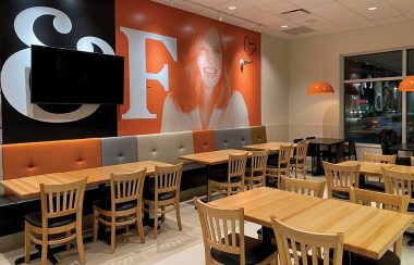 l'intérieur du restaurant, des tables avec un mur noir et orange