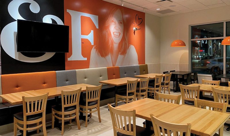 l'intérieur du restaurant, des tables avec un mur noir et orange