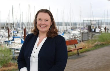 A woman standing in front of the docks where dozens of fishing boats are moored