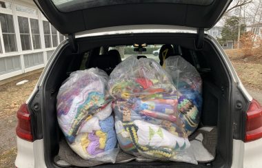 Colourful blankets bagged and loaded in the back of a vehicle