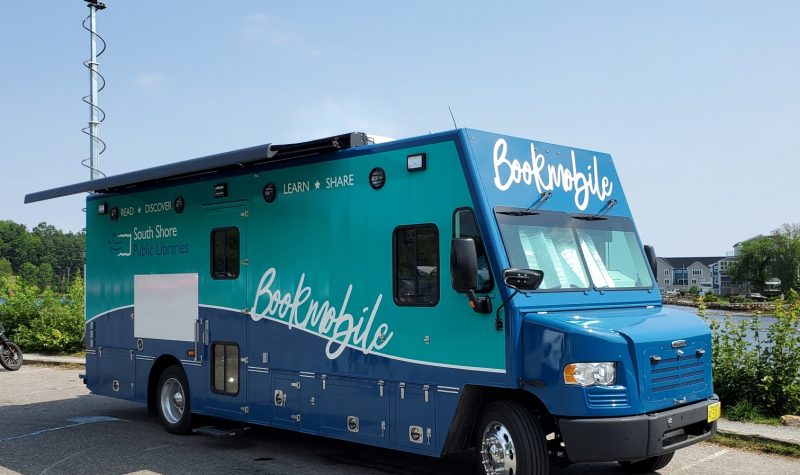 A large blue truck with Bookmobile written along sthe side is parked in front of the ocean