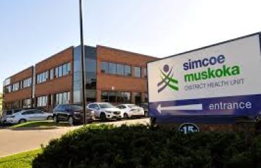 Logo du bureau de santé de Simcoe Muskoka, l'édifice avec des voitures dans le stationnement